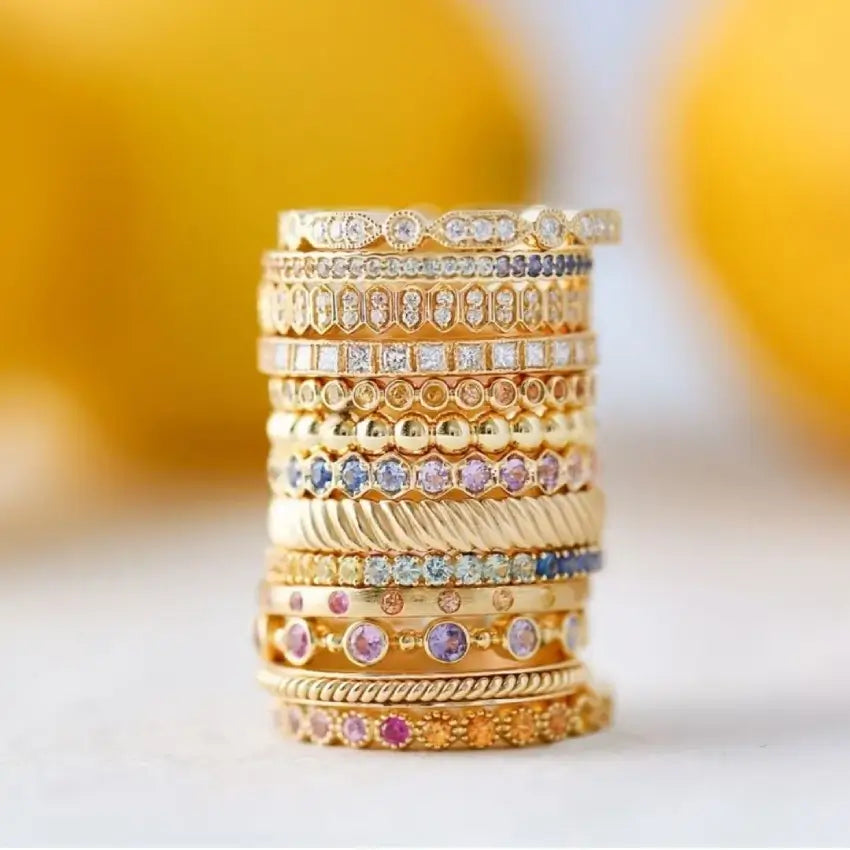 A stylish stack of gold rings embellished with shimmering diamonds and deep blue sapphires, highlighting their opulent design